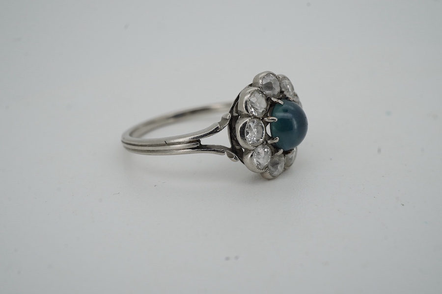 A sapphire and diamond cluster ring, early 20th century, set with a cabochon sapphire measuring approximately 5 x 5 x 3mm, within a border of circular-cut diamonds totalling approximately 0.90 carats, size M, gross weigh